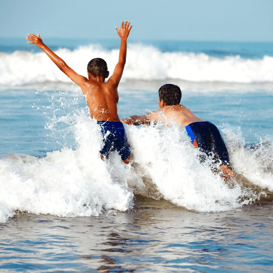 Two children enjoying a wave in clean water